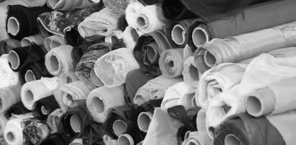 Fabric rolls stacked in a textile warehouse, raw materials ready for industrial processing.